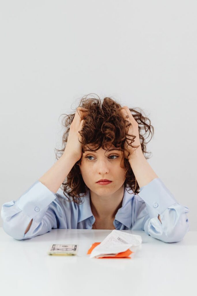 Woman in Blue Long Sleeve Shirt Holding Her Head